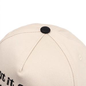 Close-up of beige cotton baseball cap featuring precise black letter embroidery