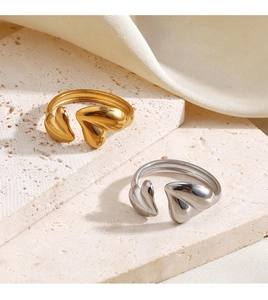 Detailed view of gold and silver open heart rings on a premium stone tray background