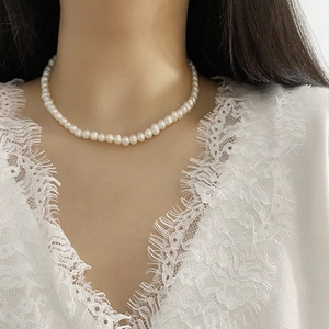 Elegant baroque freshwater pearl necklace on woman neck with white lace dress detail