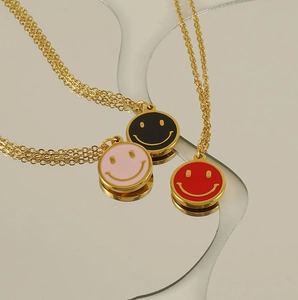 Detailed view of pink, black, and red enamel smiley face pendants on gold chains