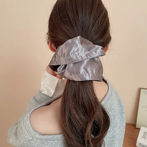 Close-up of a large silver satin hair scrunchie with silk texture on a ponytail