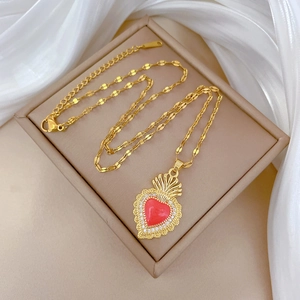 Detail of vintage gold sacred heart necklace with red enamel and pavé crystals on silk