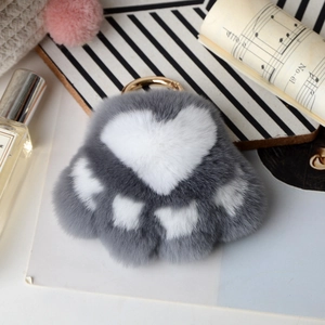 Detailed view of gray and white rabbit fur cat paw charm with a gold-tone keychain hook