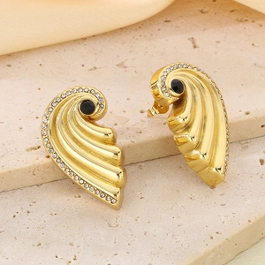 Close-up of gold wing earrings with black gemstone and pavé diamonds on stone