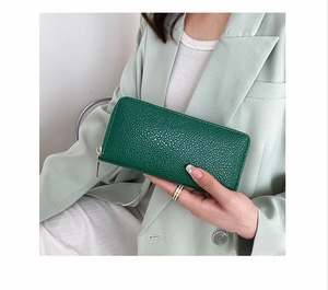 Detail of dark green pebbled leather texture on a long zip-around ladies clutch wallet