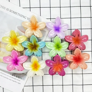 Flat lay of ten plumeria hair claw clips in vibrant gradient candy colors on mesh fabric