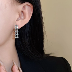Close-up of elegant silver tassel drop earrings with double-row zircon stones on model