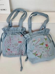 Denim drawstring tote bag with colorful embroidery of stars and cherries in light blue