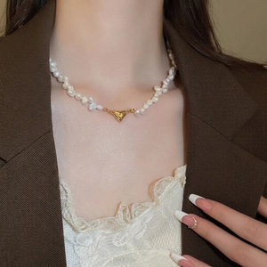 Baroque freshwater pearl necklace with 18K gold heart pendant on model in brown suit