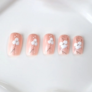 Faux ongles rose nude brillant avec motifs floraux blancs et détails de branches fins