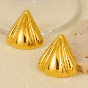Macro detail of geometric gold earrings with radial texture on a minimalist background