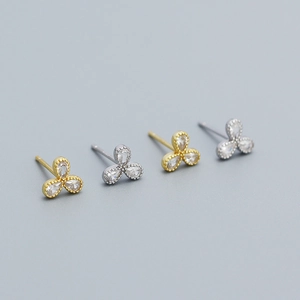 Close-up of gold and silver clover stud earrings with sparkling cubic zirconia stones