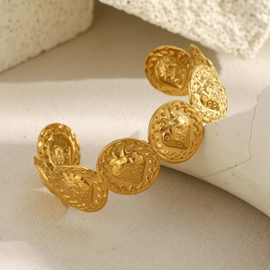 Détail d'un bracelet en acier doré 18K avec des breloques à motifs de fraises texturées