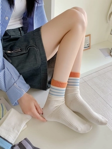 Gros plan de chaussettes en coton côtelé avec rayures orange et bleues sur fond blanc