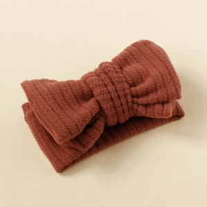 Close-up of brown textured fabric baby headband featuring a large knitted bow design