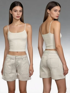 Dettaglio di crop top in maglia crema e pantaloncini cargo beige su una modella