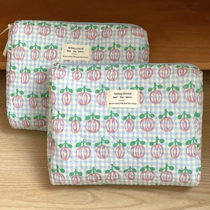 Close-up of blue checkered quilted makeup bags with floral print and zipper closure