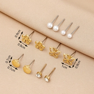Close-up of 6 pairs of gold pearl and clover stud earrings with dimension markings