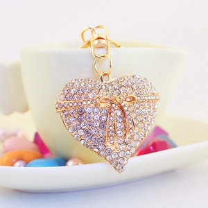 Golden heart-shaped keychain with crystal rhinestones and a delicate bow tie on a cup