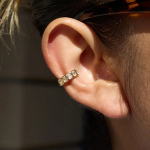 Detail of a gold ear cuff set with rectangular zircons on ear without piercing
