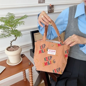 Detailed texture of orange corduroy handbag with Keep Smiling colorful prints