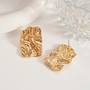 Macro detail of irregular pleated gold square earrings with polished metallic texture