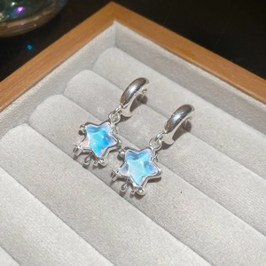 Detail of star-shaped earrings with faux opal inlay and silver drip diamond accents
