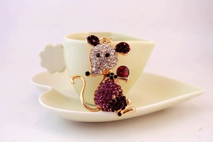 Detail of golden mouse keychain with purple crystals in a heart-shaped teacup