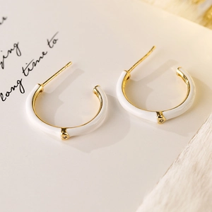 White enamel C-shaped hoop earrings with gold finish and small crystal accents