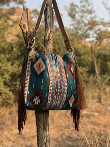 Detail of bohemian woven tote bag showing geometric patterns and leather fringe hanging