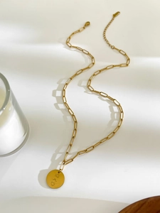 Detailed view of 18K gold paperclip chain necklace with a sun engraved round pendant
