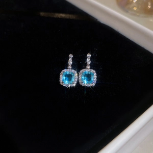 Close-up of square light blue gemstone earrings with micro-pave zircon on black velvet