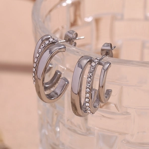 Close-up of triple-layer C-shaped silver earrings with sparkling rhinestone crystals