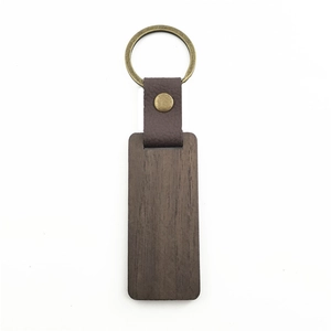 Detail of dark walnut wood keychain with brown leather strap and brass metal ring