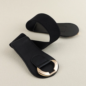 Detail of black elastic waist belt featuring a geometric gold metal buckle and faux leather finish