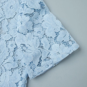 Macro detail of intricate light blue floral lace fabric on three-piece casual set