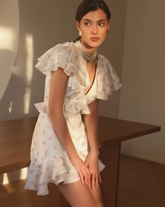 Détail des poignets volantés et de l'imprimé floral sur cette robe blanche en V