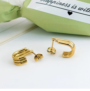 Detail of gold U-shaped titanium steel earrings with triple ribbed texture and butterfly back
