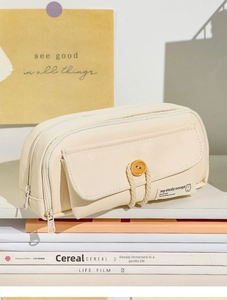 Detail of beige canvas pencil case with wooden button flap and aesthetic woven tag
