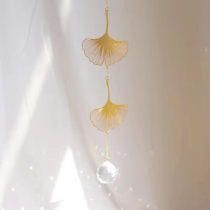 Detail of golden ginkgo leaf pendants with crystal ball prism for suncatcher decor