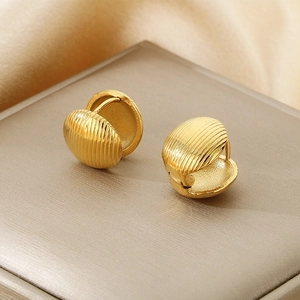 Detail of gold-plated titanium steel earrings with elegant striped texture on champagne silk