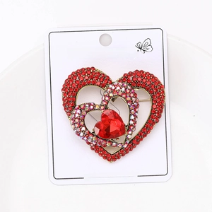 Detail of a double heart brooch with red rhinestones on a white card background