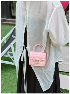 Pink quilted jelly bag with metal chain strap shown from a side view in outdoor setting