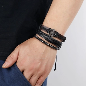 Detail of multi-layer leather bracelet set with Tree of Life charm on male wrist