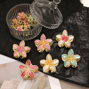 Detailed close-up of colorful bohemian flower hair claws with elegant gold metal finish