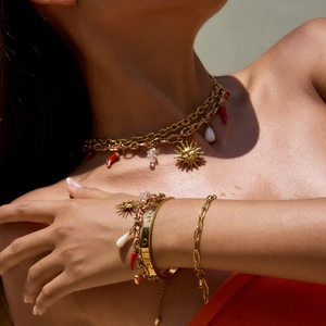 Detail of colorful charm necklace and bracelet with sun and chili pendants on a model