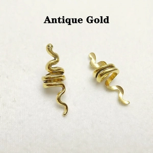 Detailed view of two antique gold spiral snake pendants for DIY hair accessories