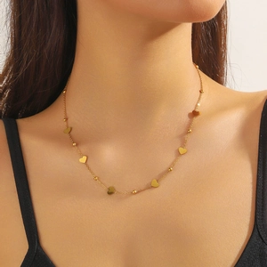 Detailed close-up of a gold heart charm necklace worn on a model neck area