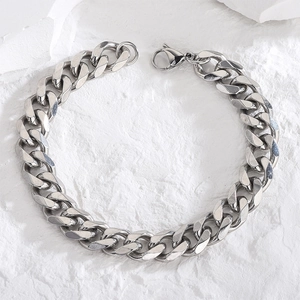 Polished silver Cuban link bracelet in stainless steel with lobster clasp on stone surface