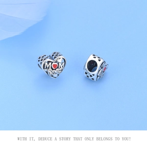 Macro detail of 925 sterling silver heart charm with red MOM engraving and cubic zirconia
